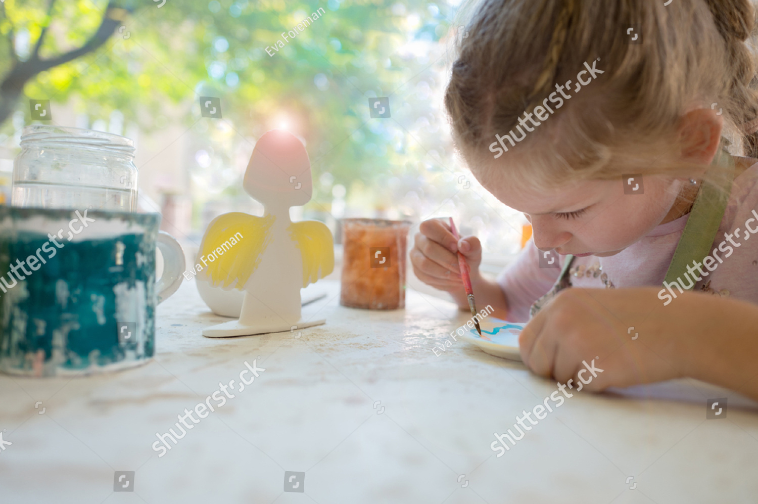 stock-photo-young-girl-painting-in-pottery-workshop-using-colourful-paints-and-brush-725047486.jpg