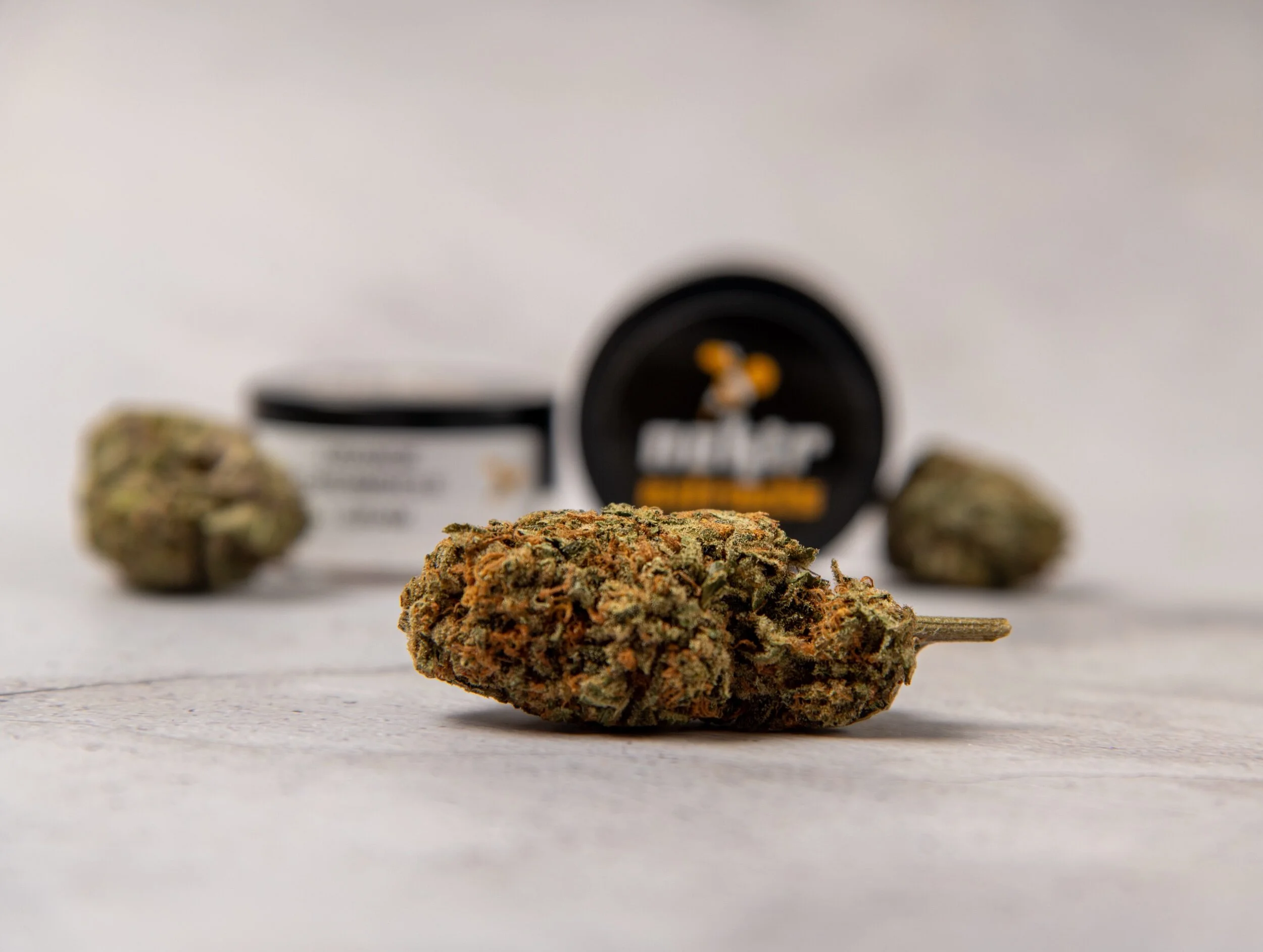 Close-up of cannabis buds with a container in the background.