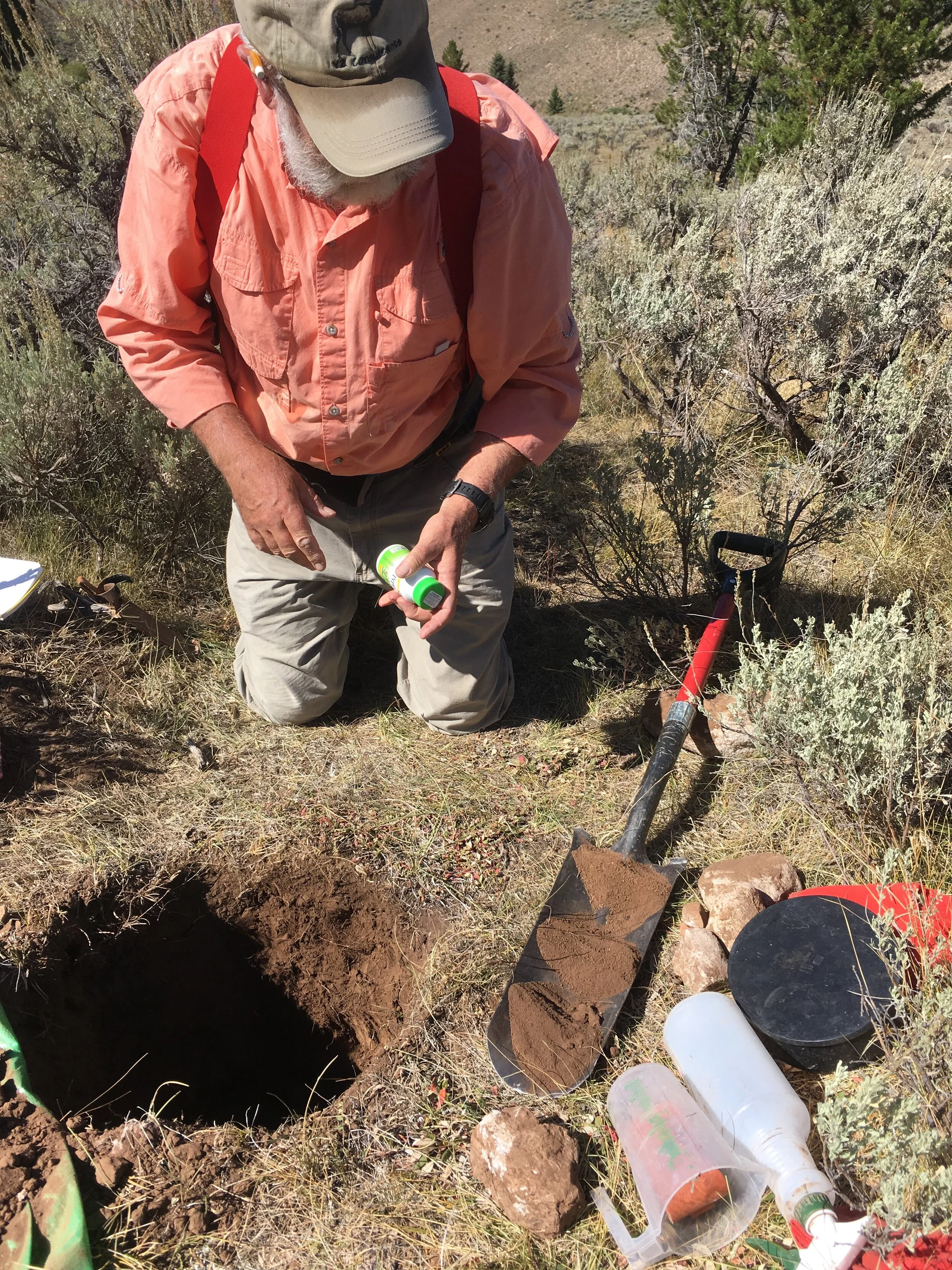 Dr. Chuck Butterfield examining soil from different horizons within the sample hole.