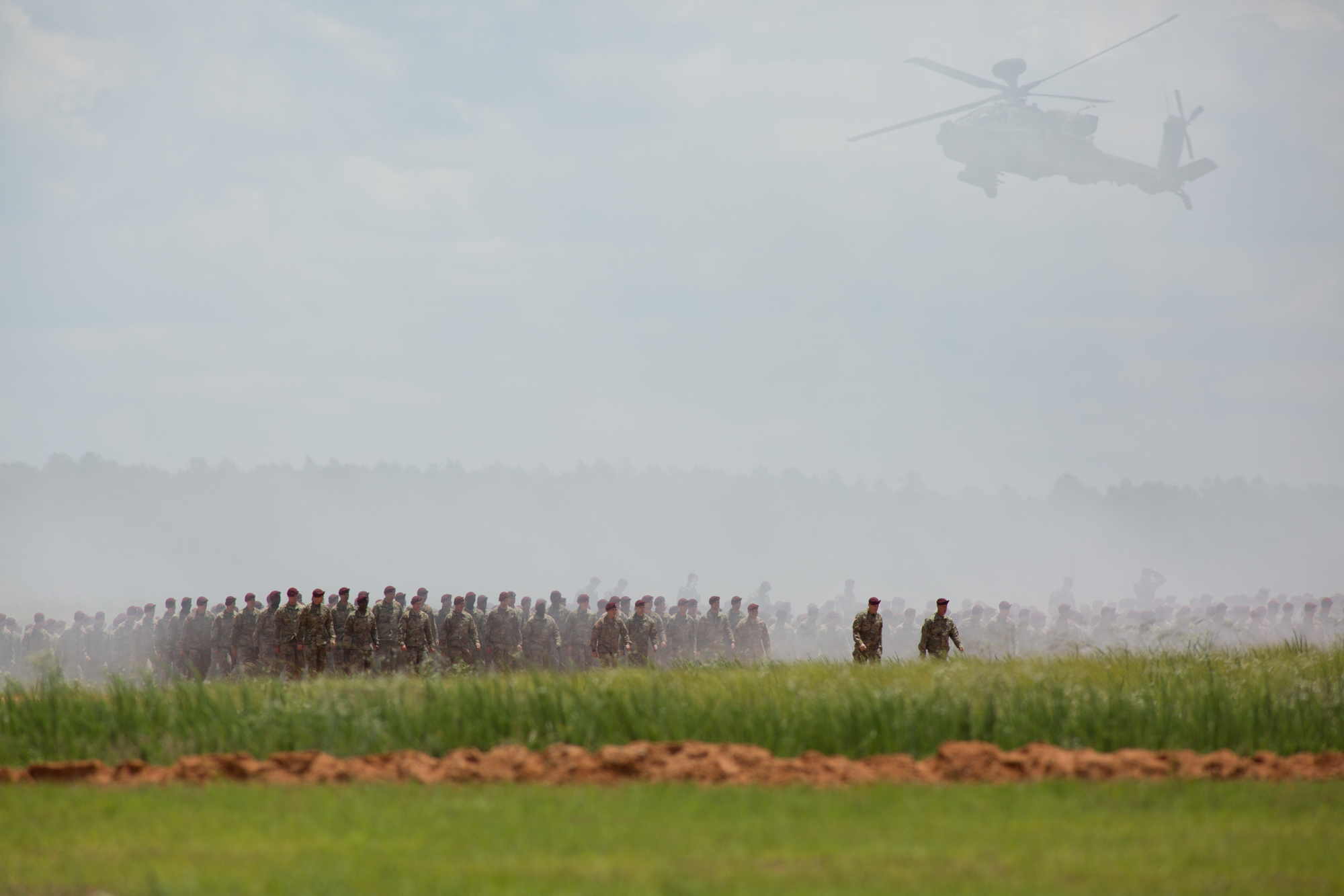  With an Army AH-64 Apache helicopter passing above, Paratroopers from the 82nd Airborne Division march across Sicily Drop Zone as part of the Airborne Review at Fort Bragg, N.C., on Thursday, May 25, 2017.&nbsp; 