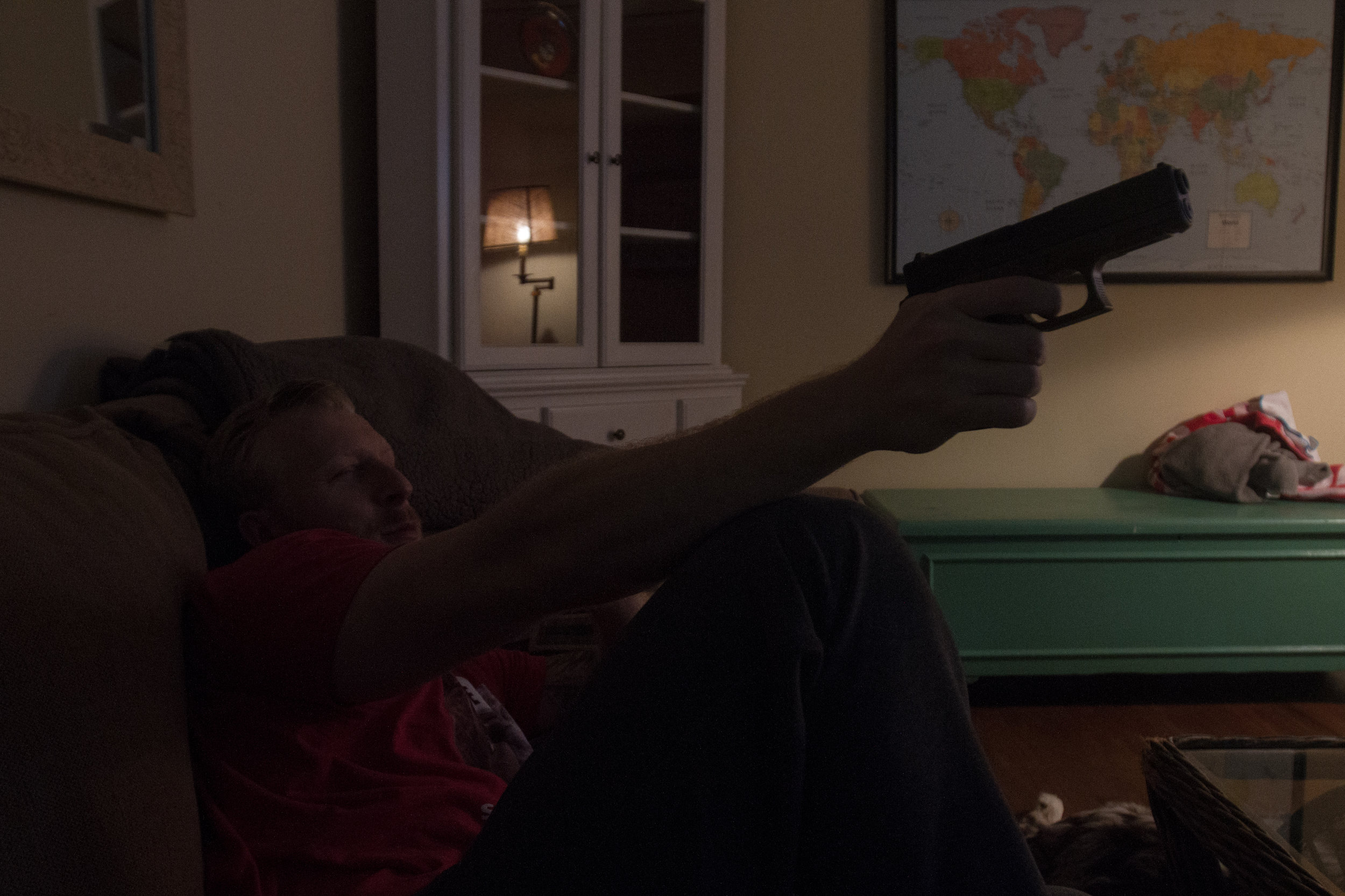 While watching TV, Fontenot practices aiming his pistol, which he keeps beside his bed. Fontenot keeps another in his car at all times.