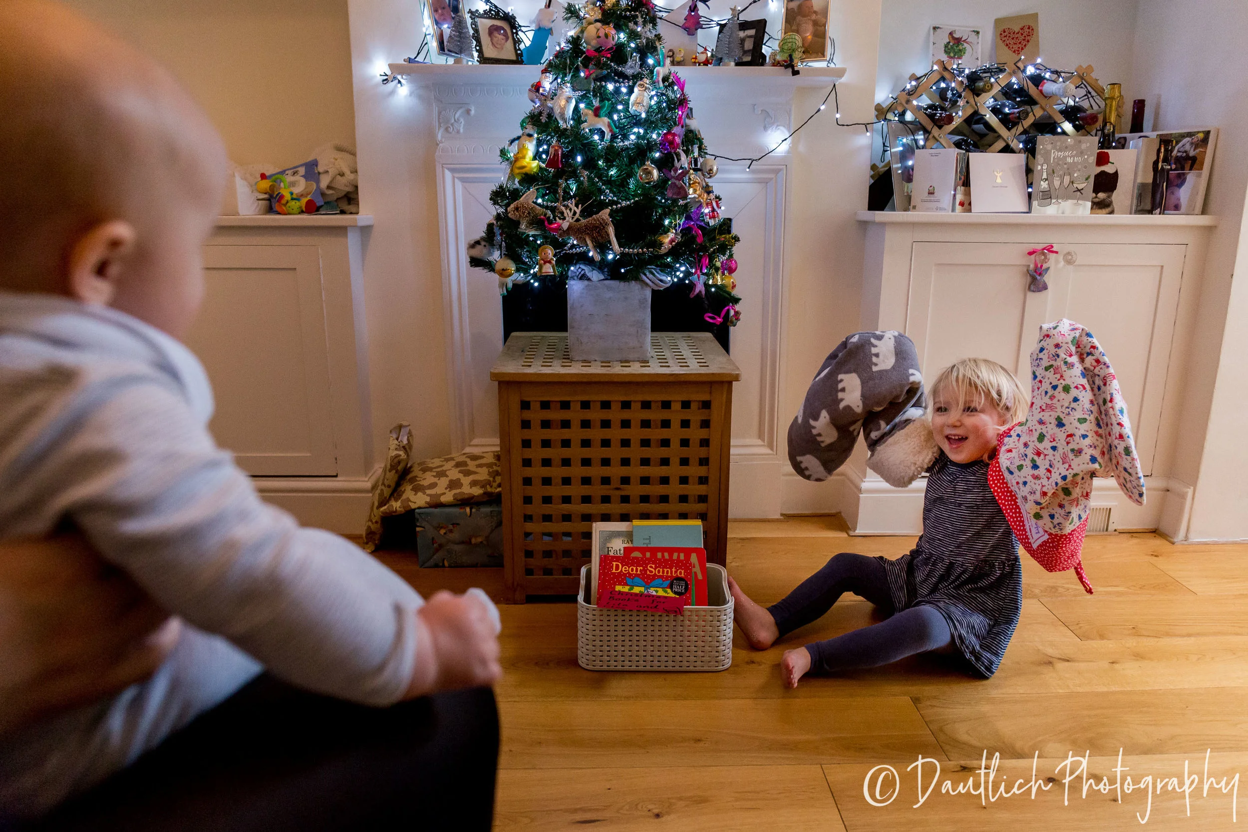 Lila is being silly and putting the Christmas stockings on her arms to entertain her sister Cleo.