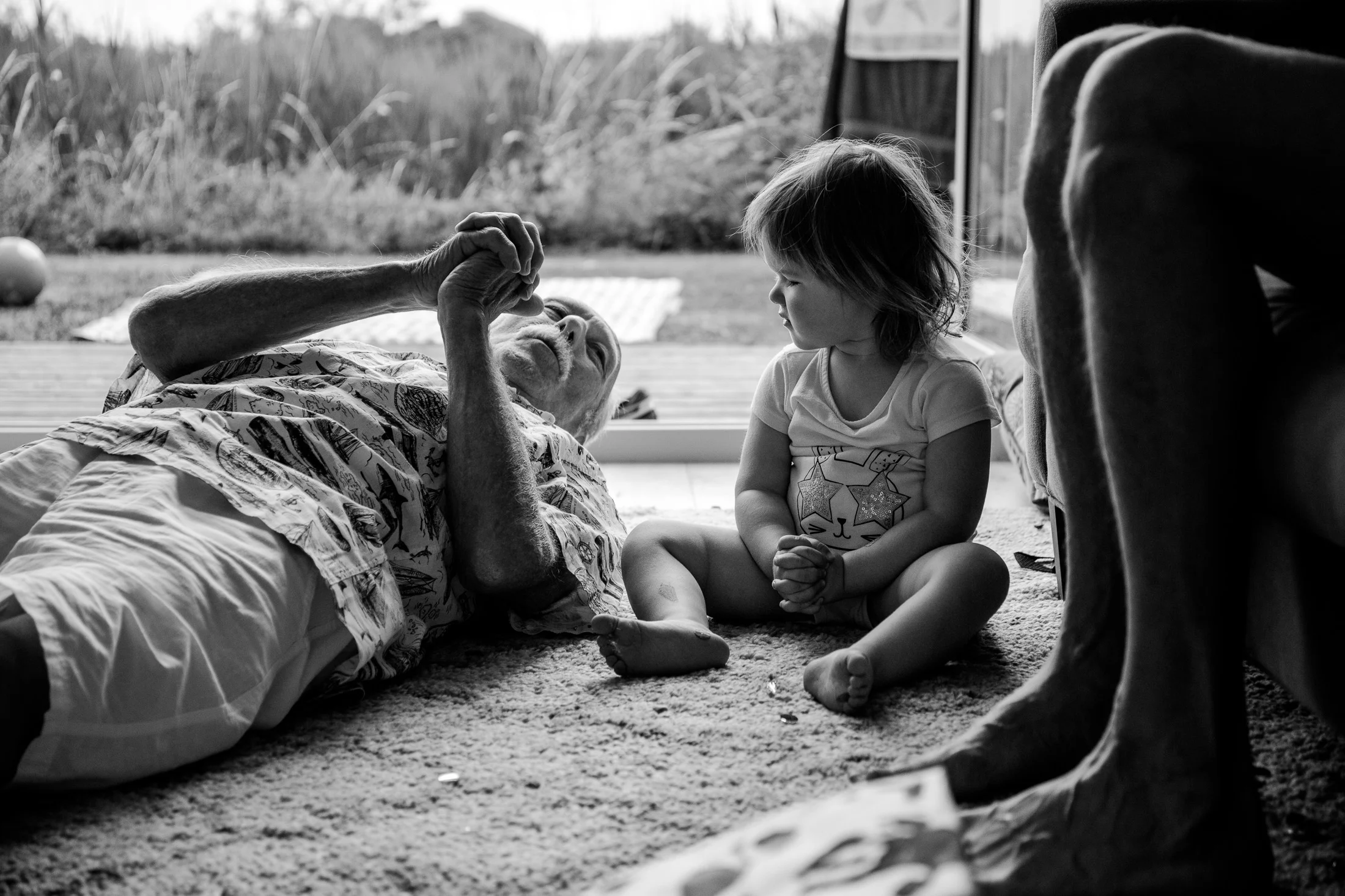 Toddler watching and mimicking grandfather's zen fists during natural family photo session.