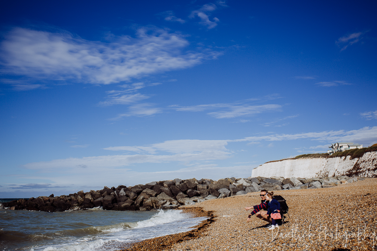 Hazel and Nick throwing rocks into the sea at Rottingdean Beach outside of Brighton.