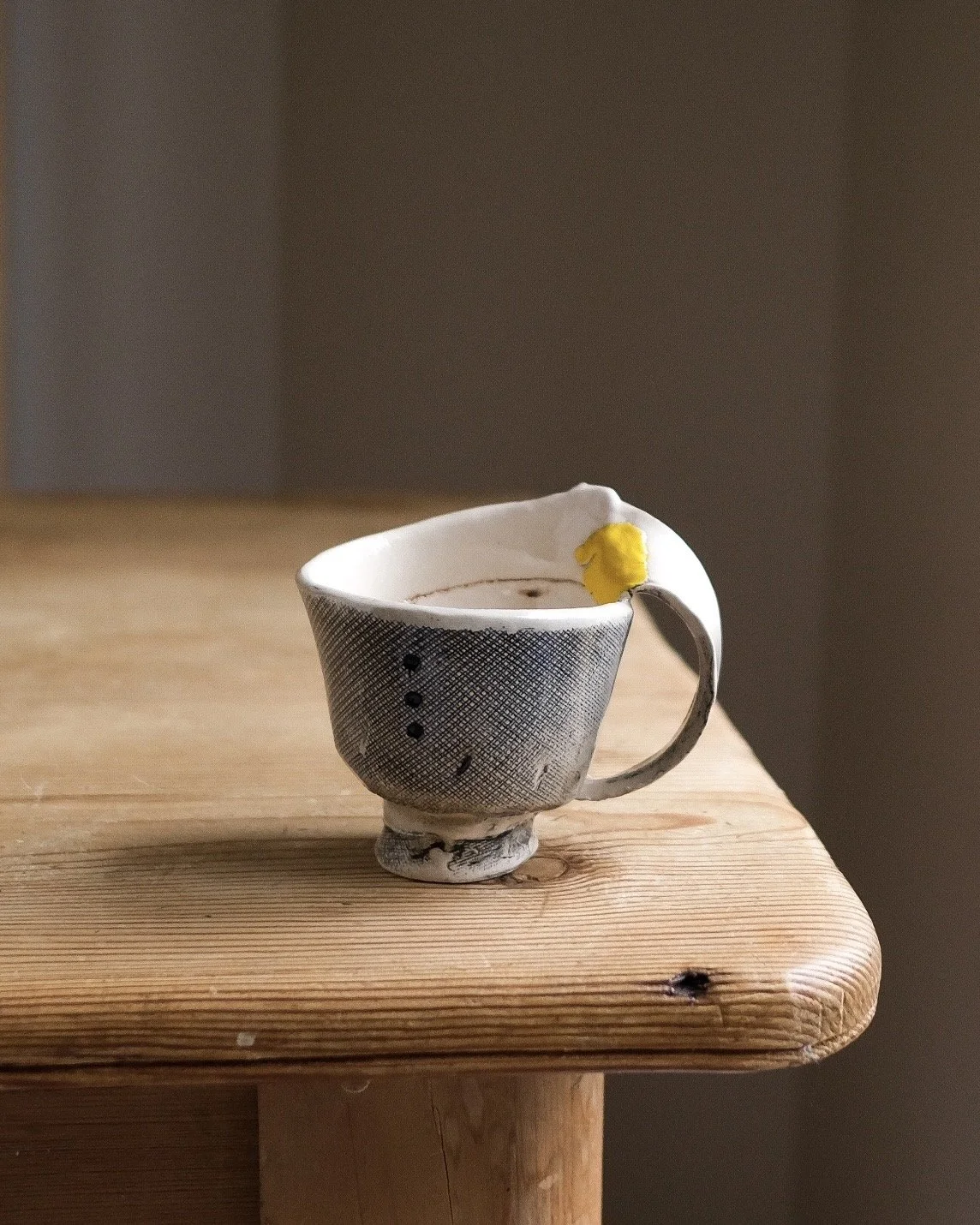 Bandaid cup with bright yellow patch on a large comfortable handle of a handbuilt cup