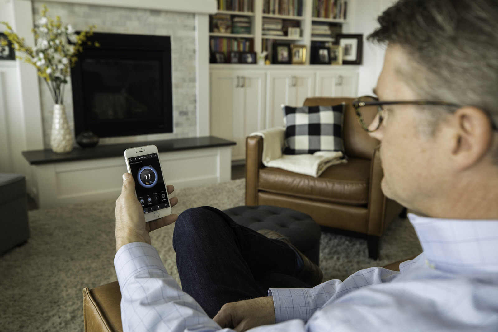 Control4_Comfort_Heating_Control_Man_Holding_iPhone_In_Living_Room_Temperature_Thermostat_Brown_Leather_Seats