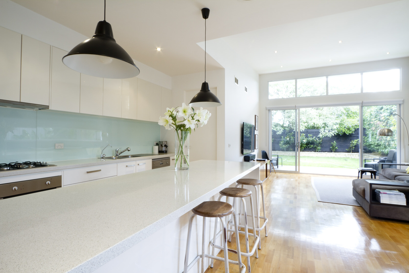 Lutron_Lighting_Kitchen_Diner_White_Cabinets_Glass_Splashback_Brown_Flooring_Leading_To_Garden_Black_Fence_Wall_Mounted_Smart TV.jpeg