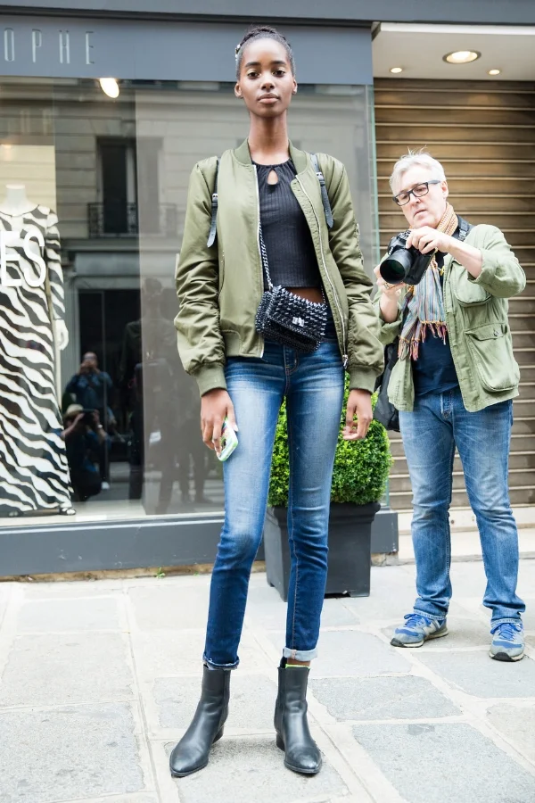 Exiting a Haute Couture Autumn/Winter 2016 show, model Tami Williams looked graceful in a casual off-duty look. She paired a green bomber jacket with a black crop top and jeans, as well as black ankle boots and a studded black shoulder bag. Still wearing the hair crown and gold makeup from her latest show, Tami makes this street cool outfit elegant via The Front Row View.