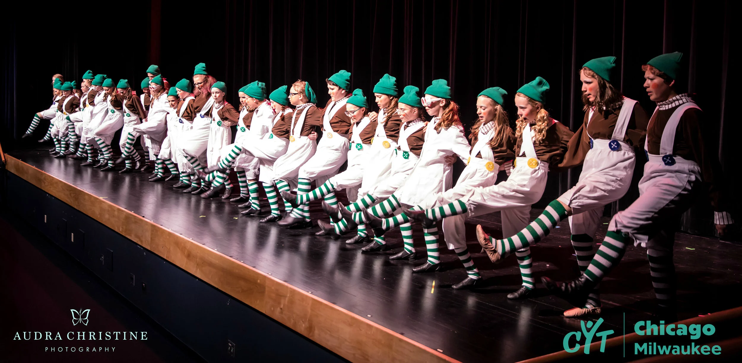 A long line of Oompa-Loompas sing and dance
