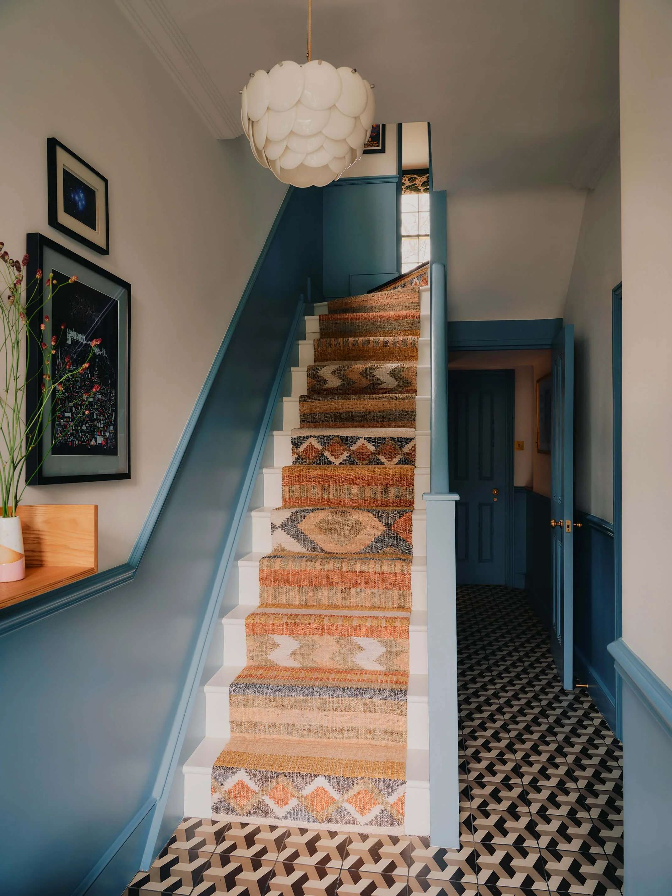 Blue staircase, woven stair runner and geometric tiled entrance way floor.