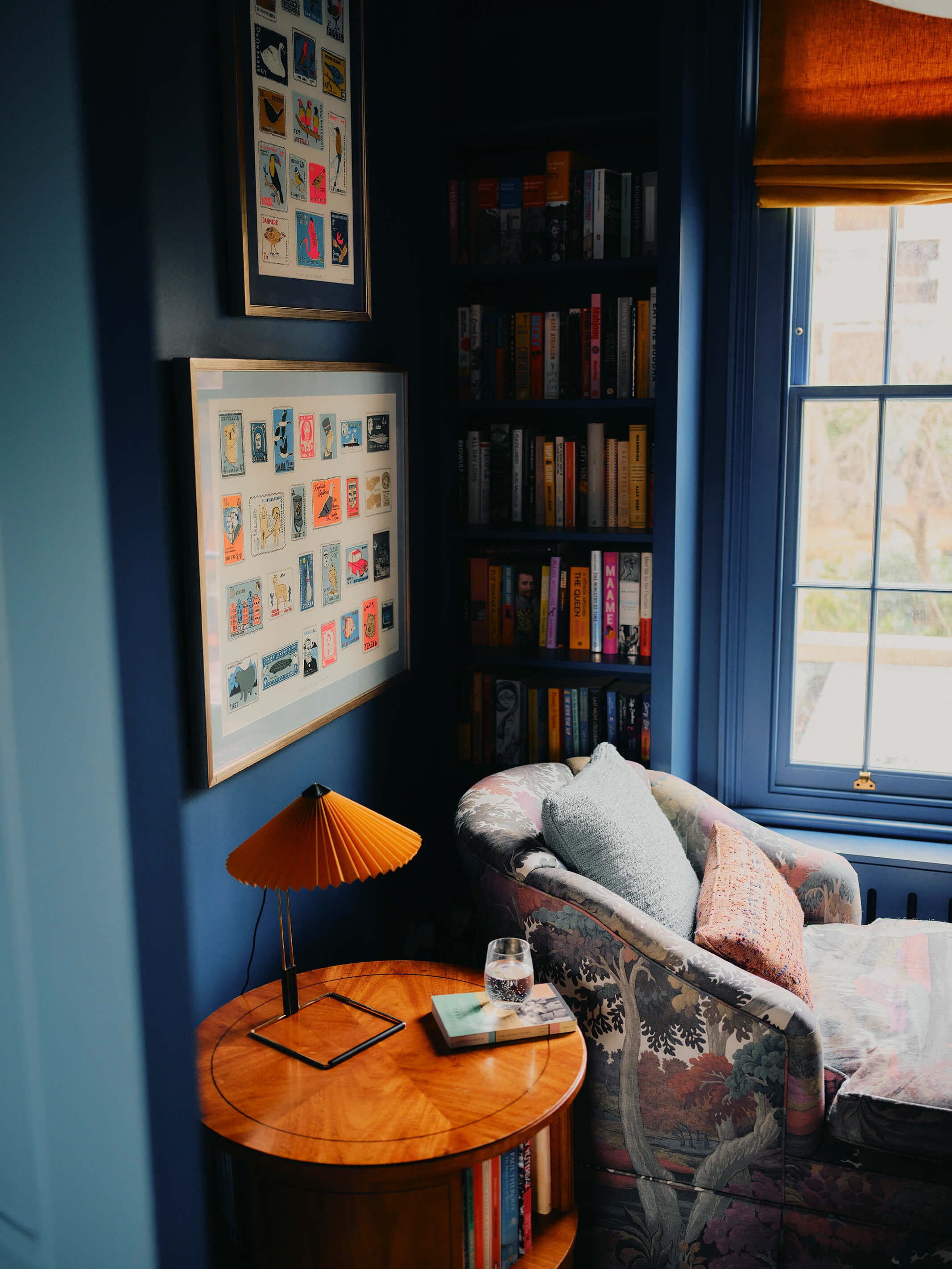 Royal Blue living room, with close up of side table with lamp, book, glass of water.