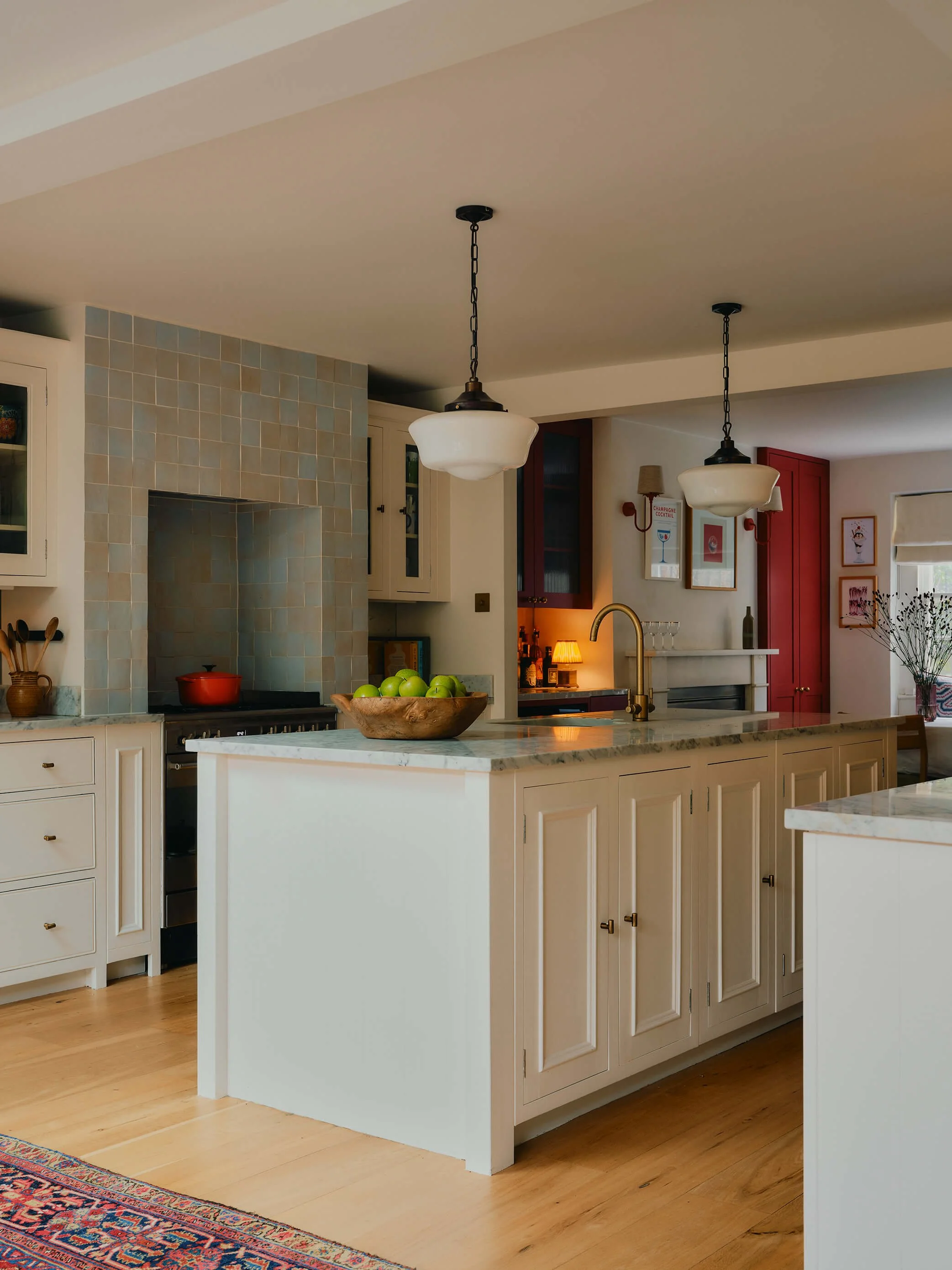 Contemporary kitchen with tiled backsplash, marble island counter top, hanging lights, and wooden floors.