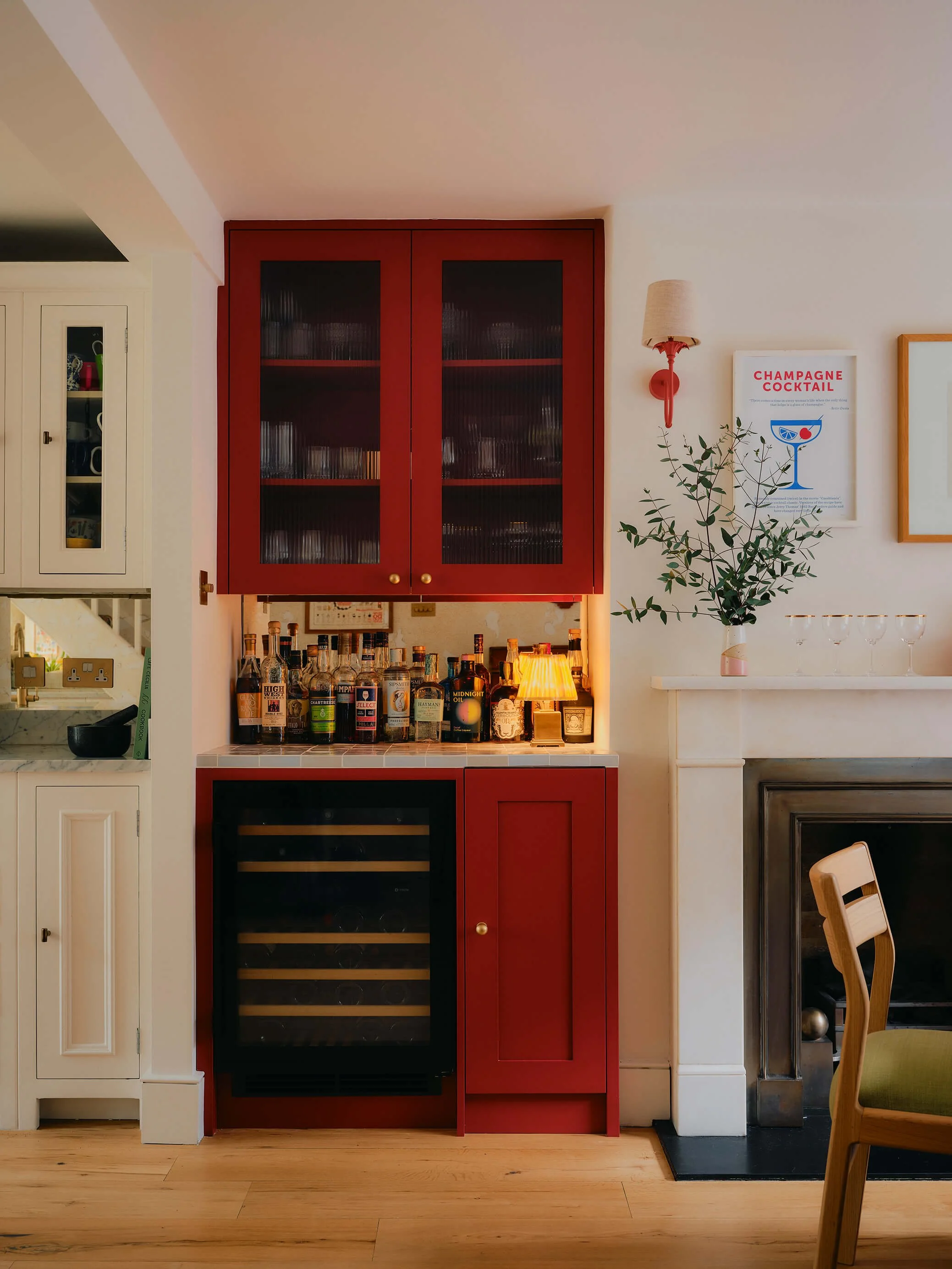 Bright red kitchen bar, with wine fridge, warm lamp on tiled surface