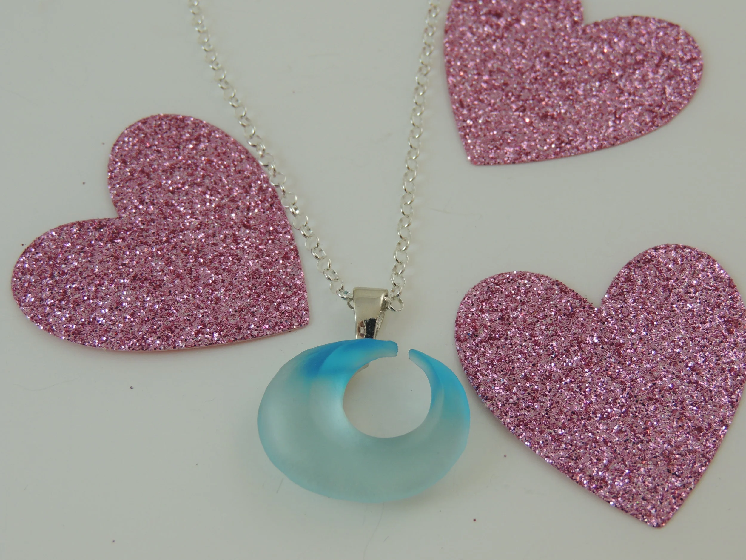 Medium - Pendant on a chain with props in the background. These will need to be removed and the empty spaces will need to be filled. Nothing is obstructing the jewelry, just the background. Careful attention is paid to the chain and take a bit longer to edit. Lighting, color balance will be fixed, as well as straightening the image and cropping.
