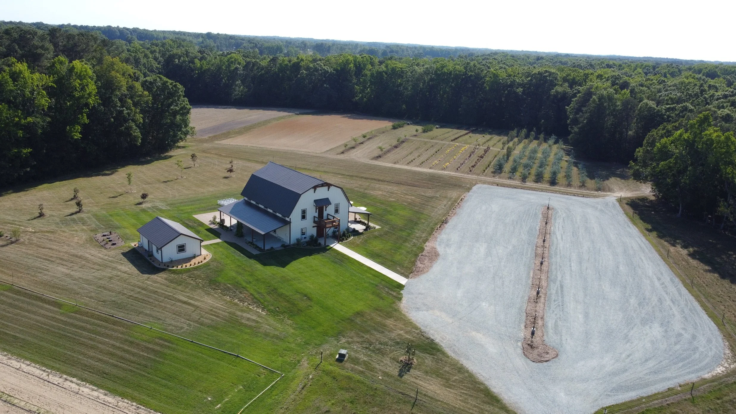 Drone shot of white barn, parking lot and entry