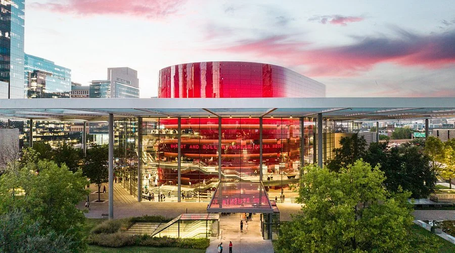 Modern building with glass walls reflecting trees and sunset sky