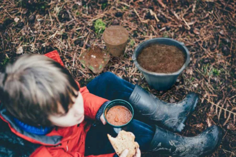 Small boy in gum boots planting outside