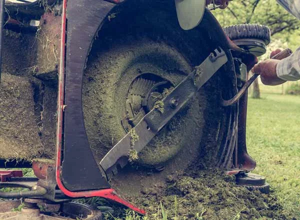 Lawn mower turned over with grass clippings