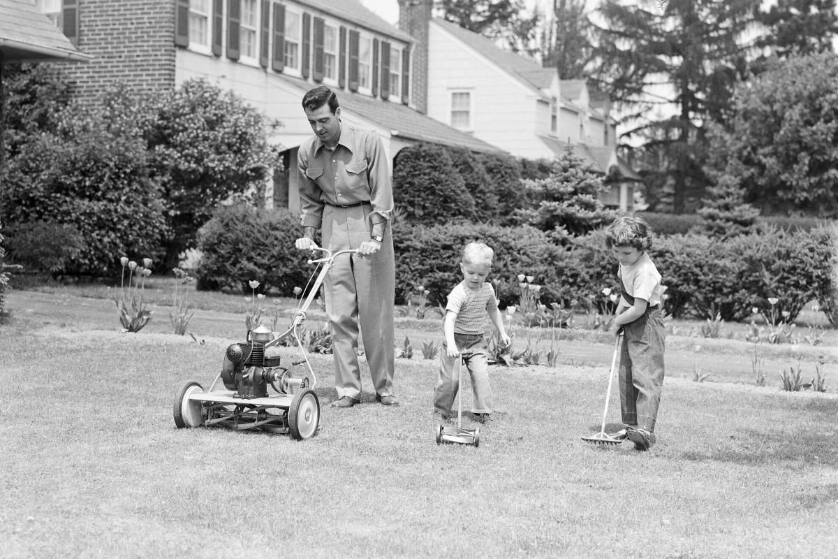 Old photo of a dad and his children lawn mowing