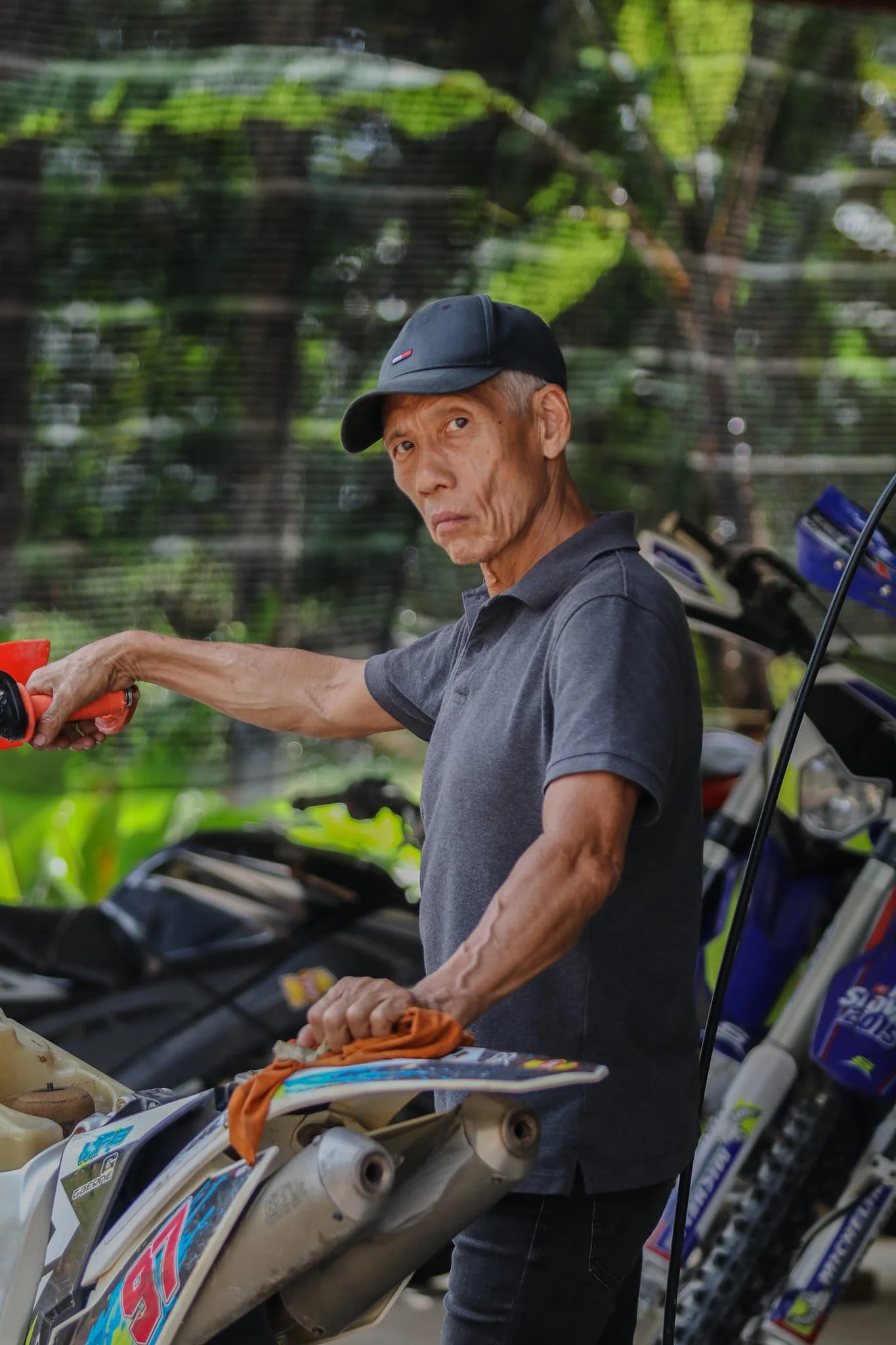 OKB (OH Kah Beng), Malaysian motorsport legend and dirt bike instructor at Most Fun Gym, preparing motorcycles at riding academy in Kampung Sungai Penchala