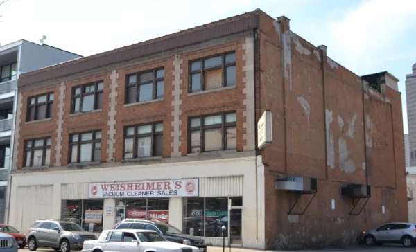  This image of the Weisheimer Building before renovation shows how the building had been modified over the years. At some point, the facade had been modernized and the original storefront windows modified.&nbsp;The north wall of the building was orig