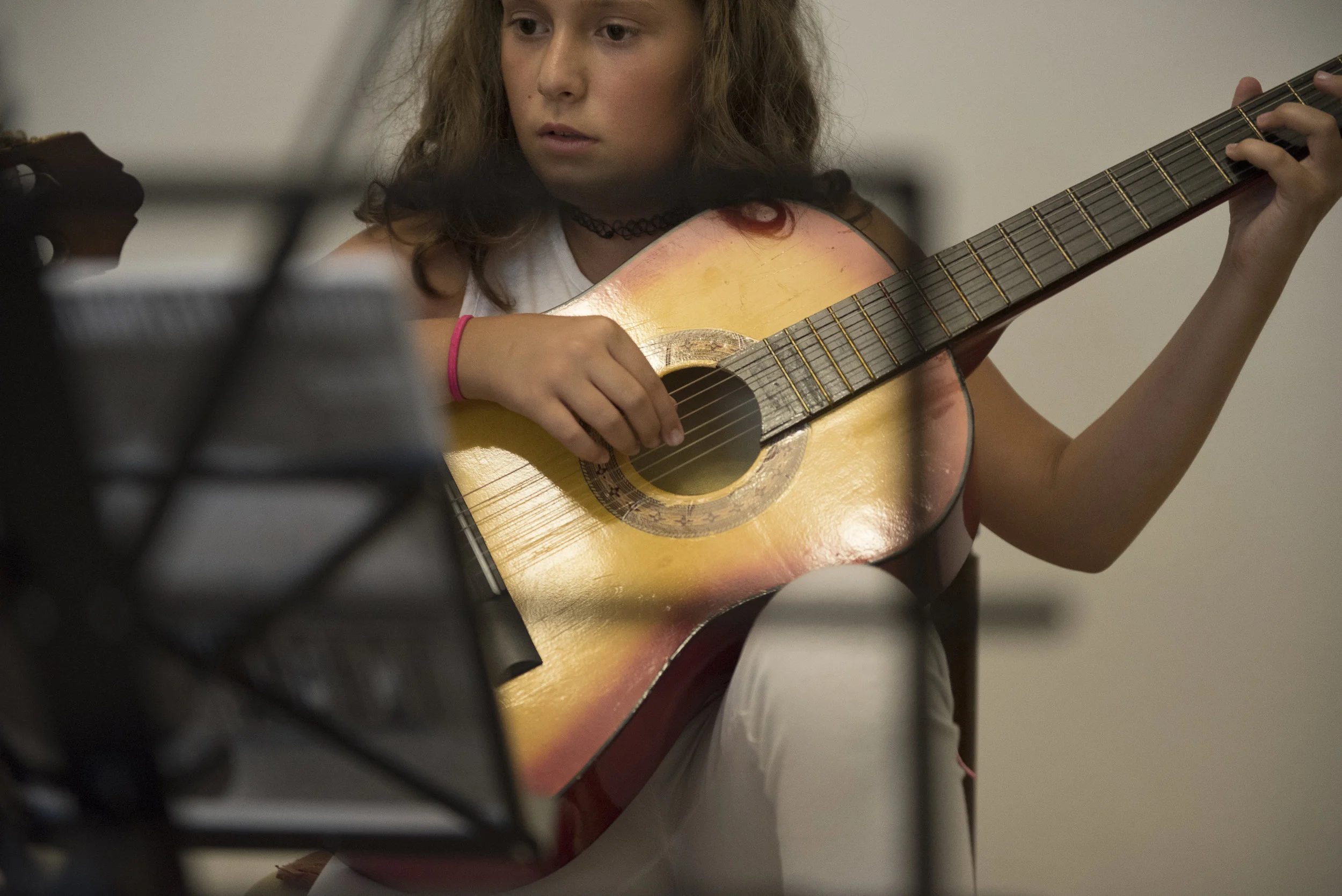 Rita Nushi plays guitar during her practice session with Lorik Pylla, Gjakova, Kosovo, July, 10, 2017. Nushi goes to Lorik Pylla's house for her private lessons and her father waits outside for her.