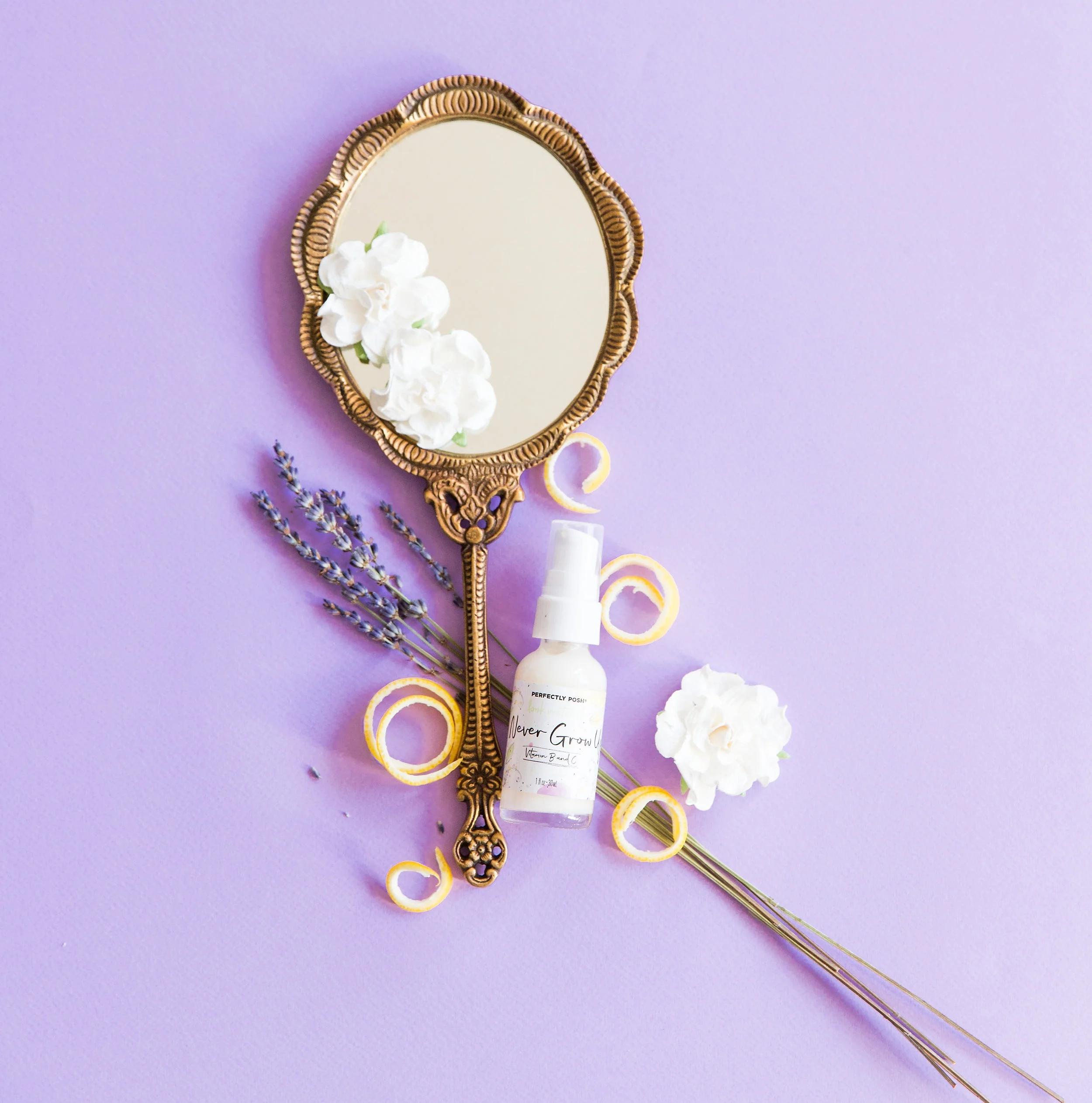 Never Grow Up Serum with a hand mirror on a purple background.