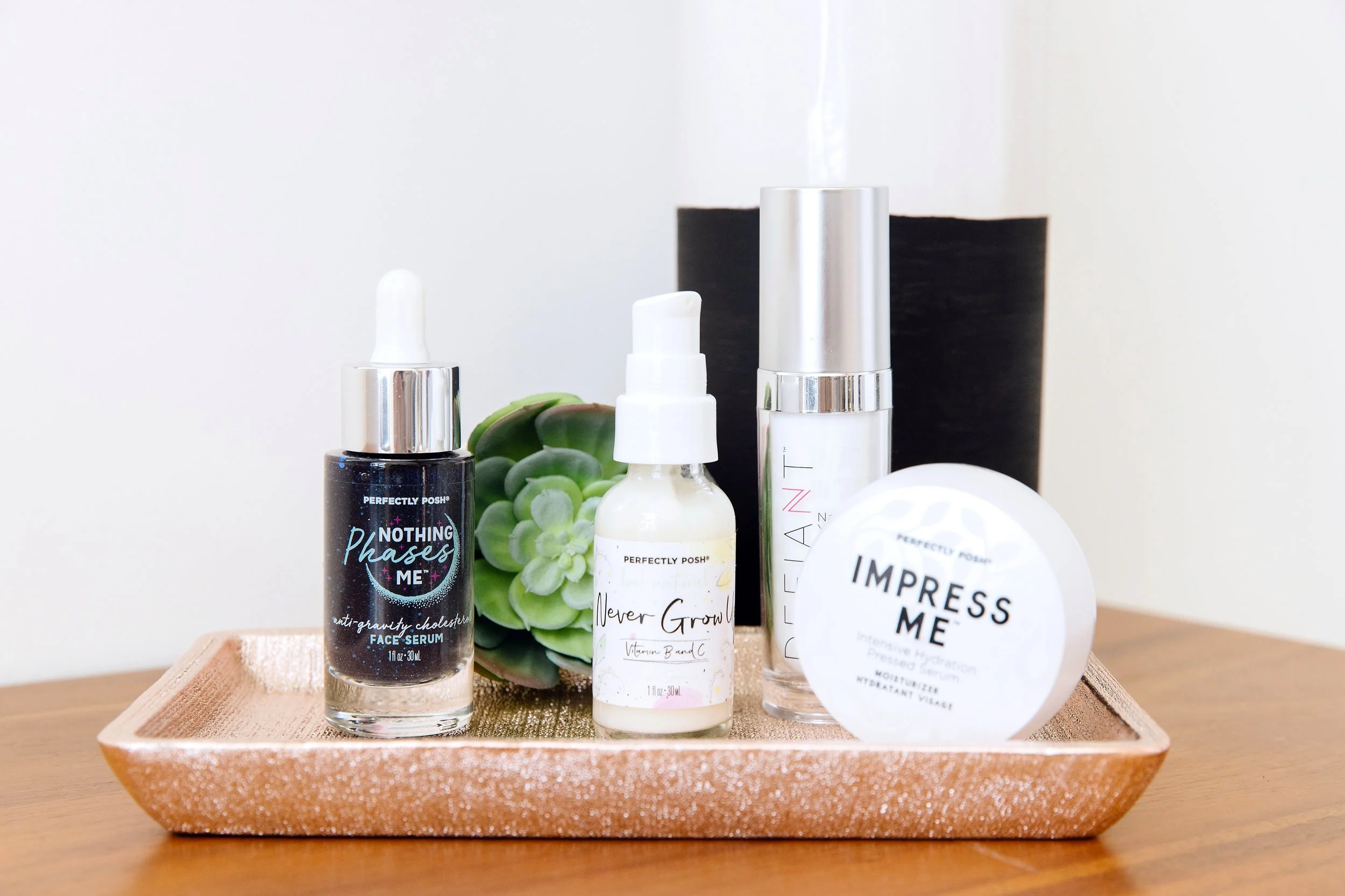 Perfectly Posh collection of face serums, including vegan Nothing Phases Me Anti-Gravity Cholesterol Face Serum, antioxidant Never Grow Up Face Serum with vitamins B and C, Defiant Naked Youth Serum with moringa oil and micronized pearl powder, and Impress Me Intensive Hydration Pressed Serum and Moisturizer