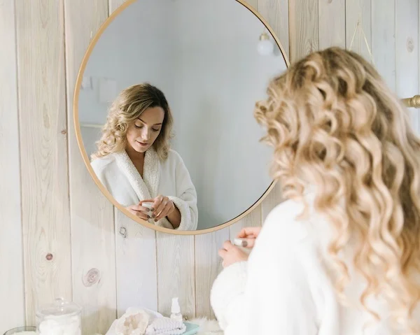 Fixing uneven and dull skin with Serves You Bright Face Cream, girl in mirror practicing brightening skin routine for dark spots and hyperpigmentation