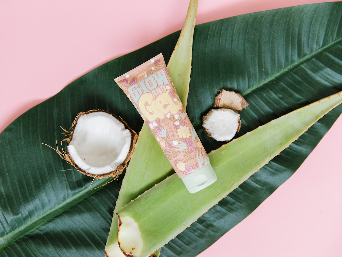 Perfectly Posh Show and Gel Gel-to-Water Body Moisturizer stylized on palm leaf with aloe vera and coconut