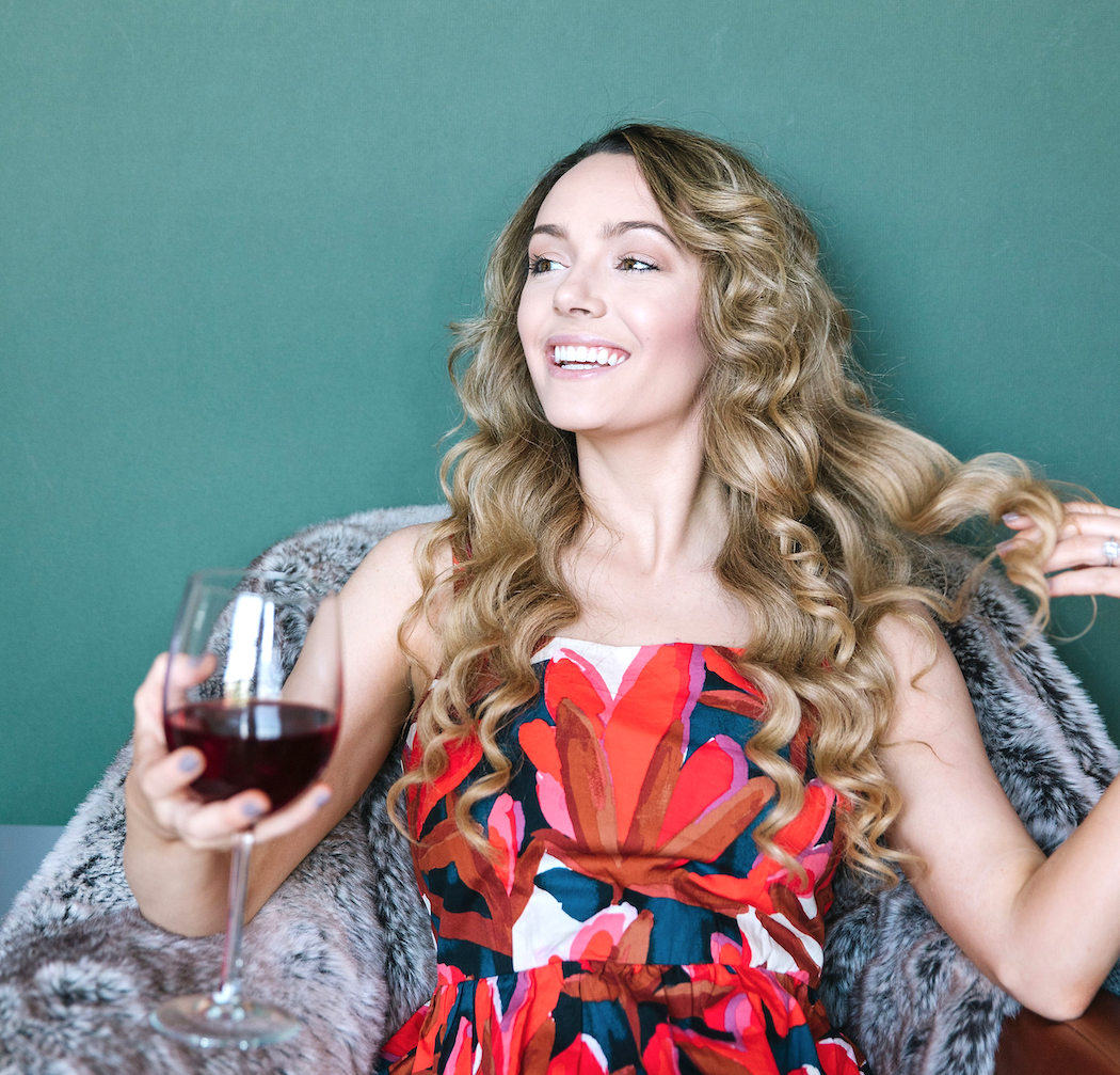 Blonde woman with curls drinking red wine with anti-aging and antioxidant resveratrol for younger looking skin
