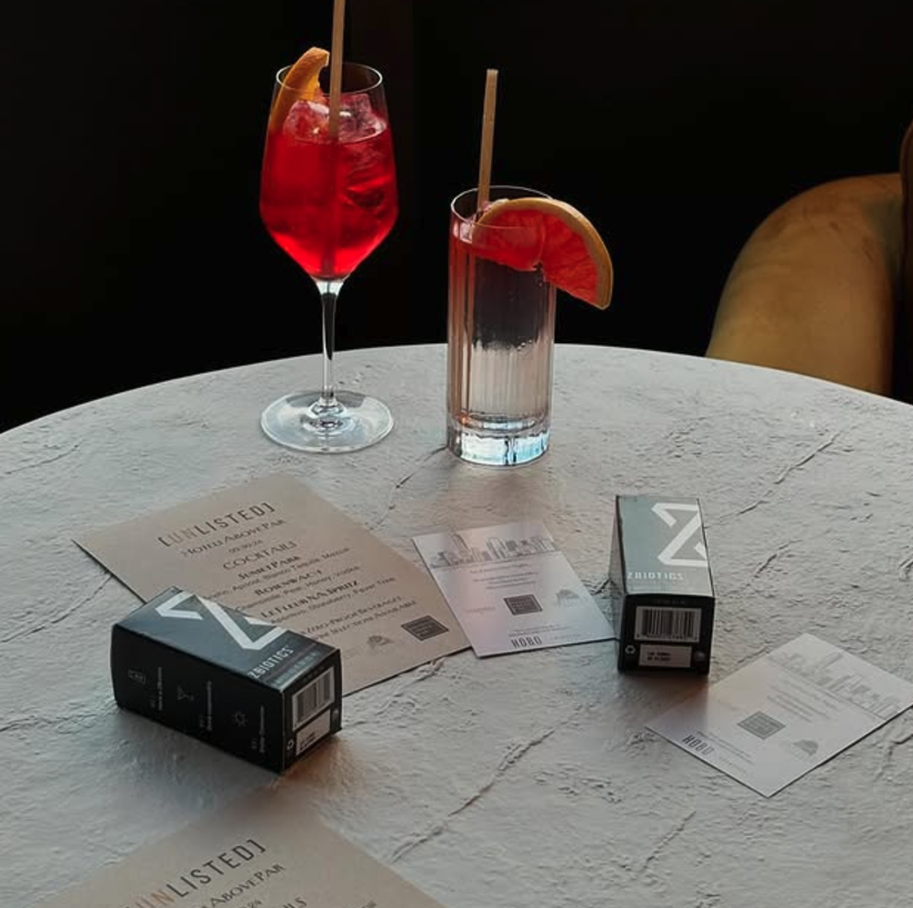ZBiotics Pre-Alcohol boxes on a bar table next to cocktails before a night out
