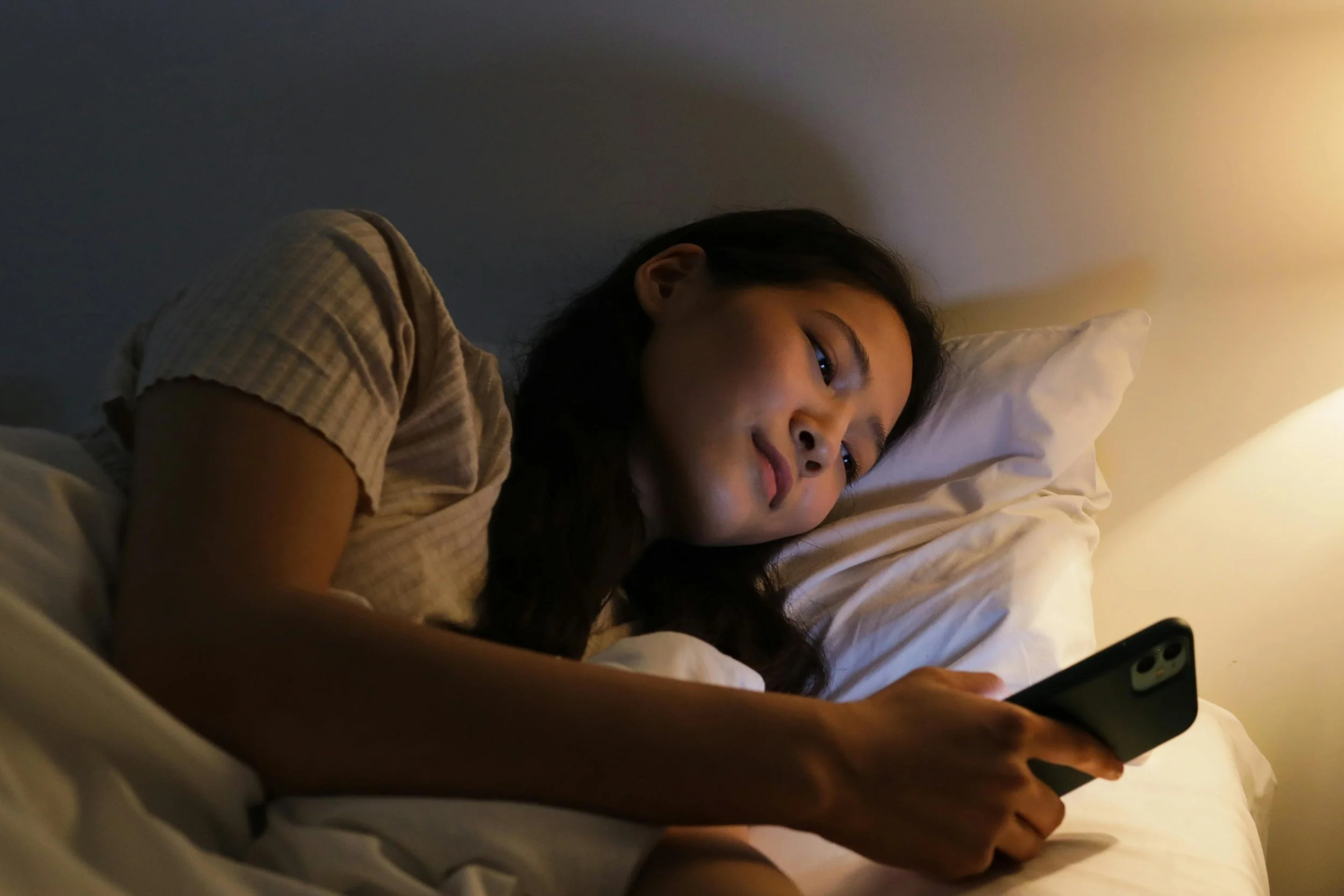 Person using a phone in bed at night