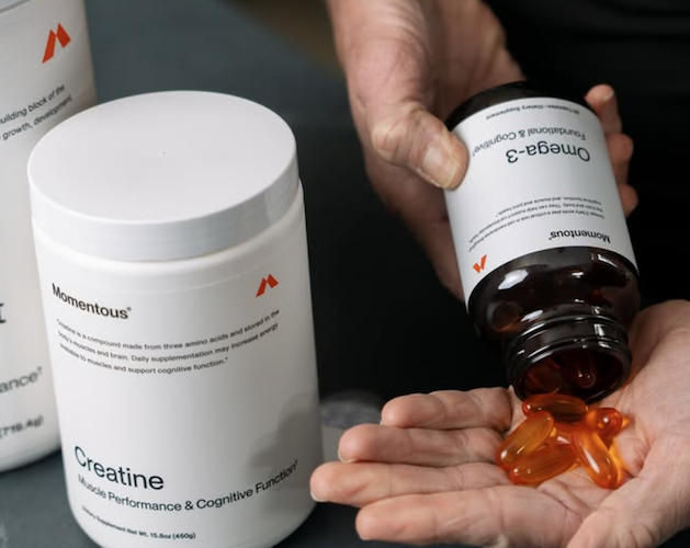 Momentous creatine supplement and omega 3 capsules being poured into hand for daily supplement routine and performance support