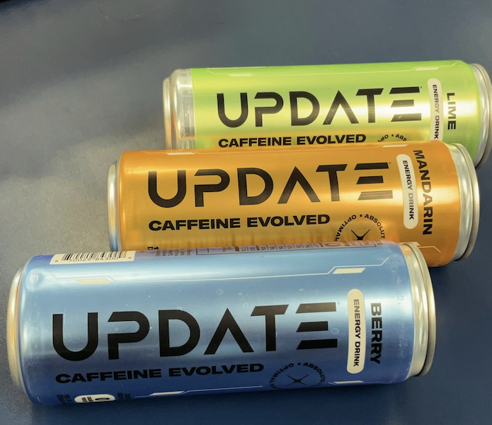Update Energy paraxanthine drink cans in Lime, Mandarin, and Berry flavors laid flat on a table