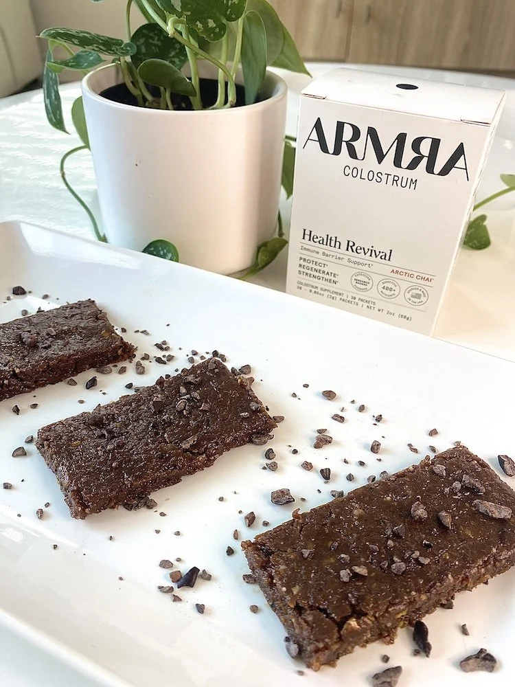 Finished no bake Armra colostrum date bars topped with cacao nibs on a white plate