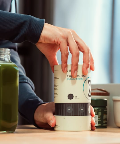 ZBiotics Sugar-to-Fiber canister on a kitchen counter next to a green smoothie