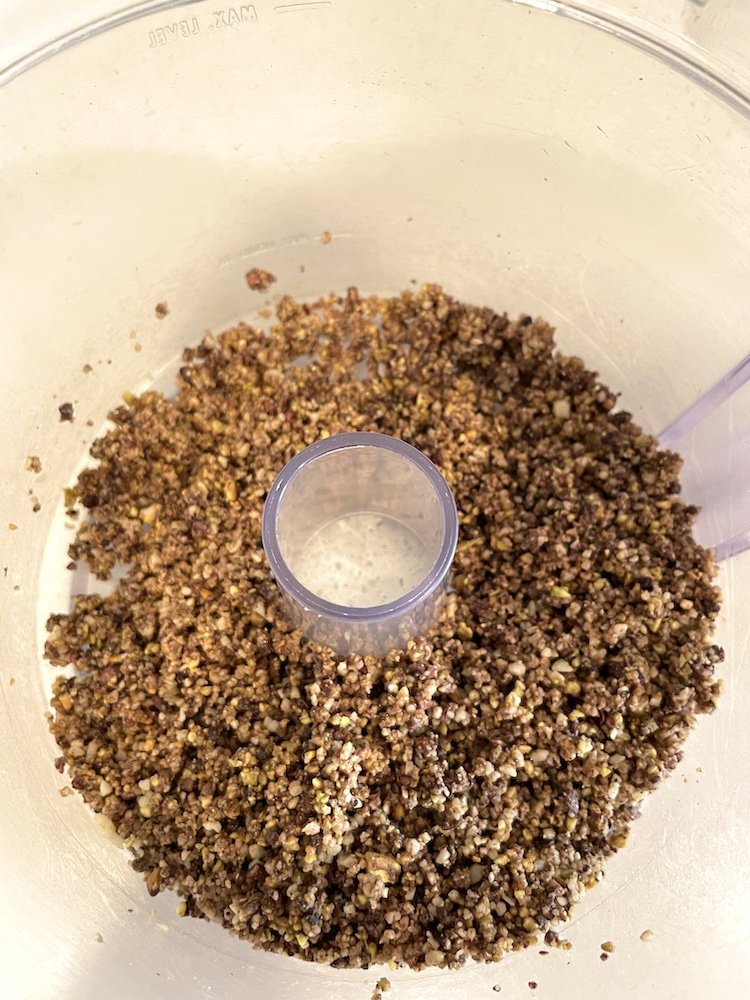 Pistachios, macadamia nuts, cacao nibs, and colostrum pulsed together in a food processor