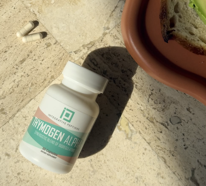 Integrative Peptides Thymogen Alpha-1 capsule bottle on a sunlit tile surface next to loose capsules