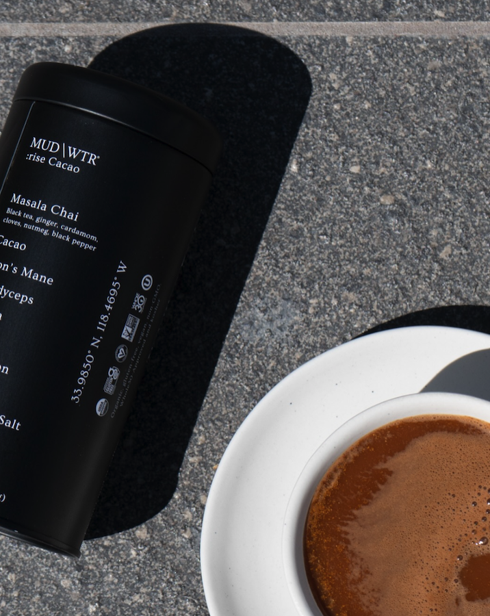 MUD/WTR tin next to a finished cup on a sunny outdoor table