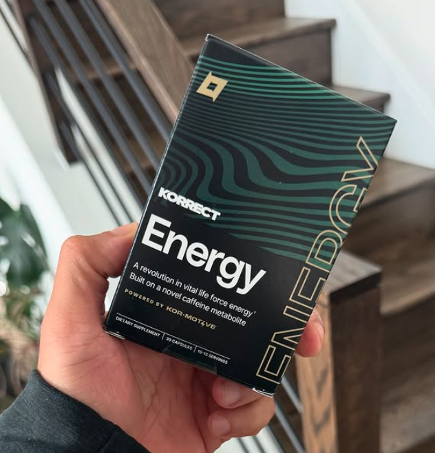 Hand holding Korrect Energy capsule box in indoor setting