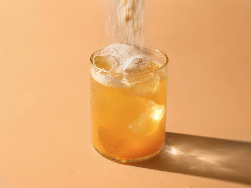 ARMRA colostrum powder being poured into a drink for gut health and digestion support