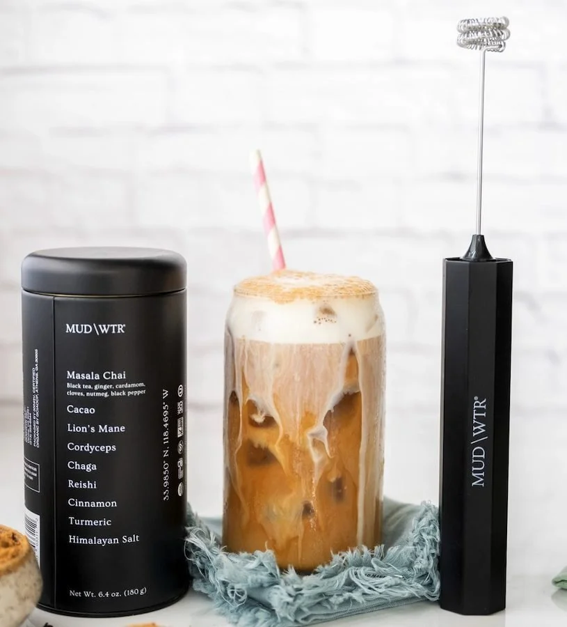 MUD WTR Original tin beside an iced latte