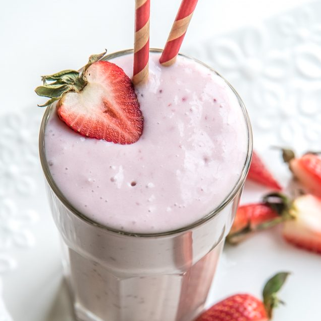 Strawberry Keto Chow shake topped with a fresh strawberry slice and two paper straws