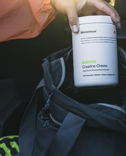 Momentous creatine chews container being placed in gym bag for portable performance support and convenient daily supplement use