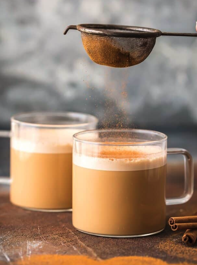 Cinnamon being sifted over frothy bulletproof coffee