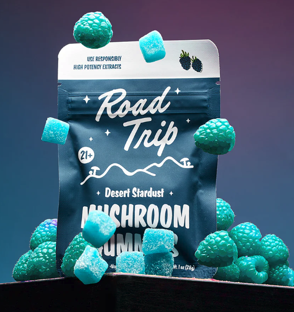 Road Trip Desert Stardust Blue Raspberry mushroom gummies pouch with teal gummy cubes scattered around it