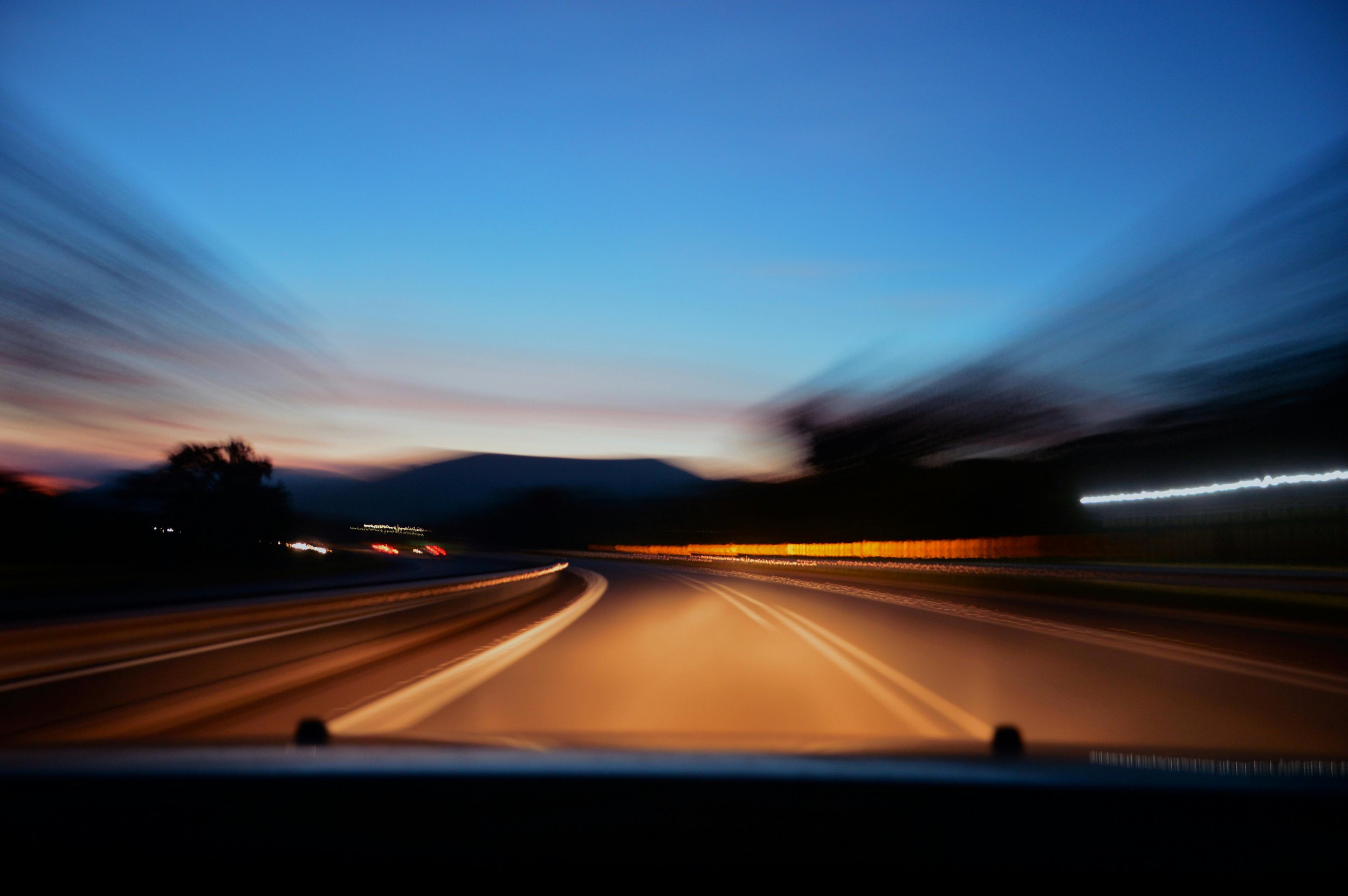 Blurred motion of a road seen from inside a moving car at dusk