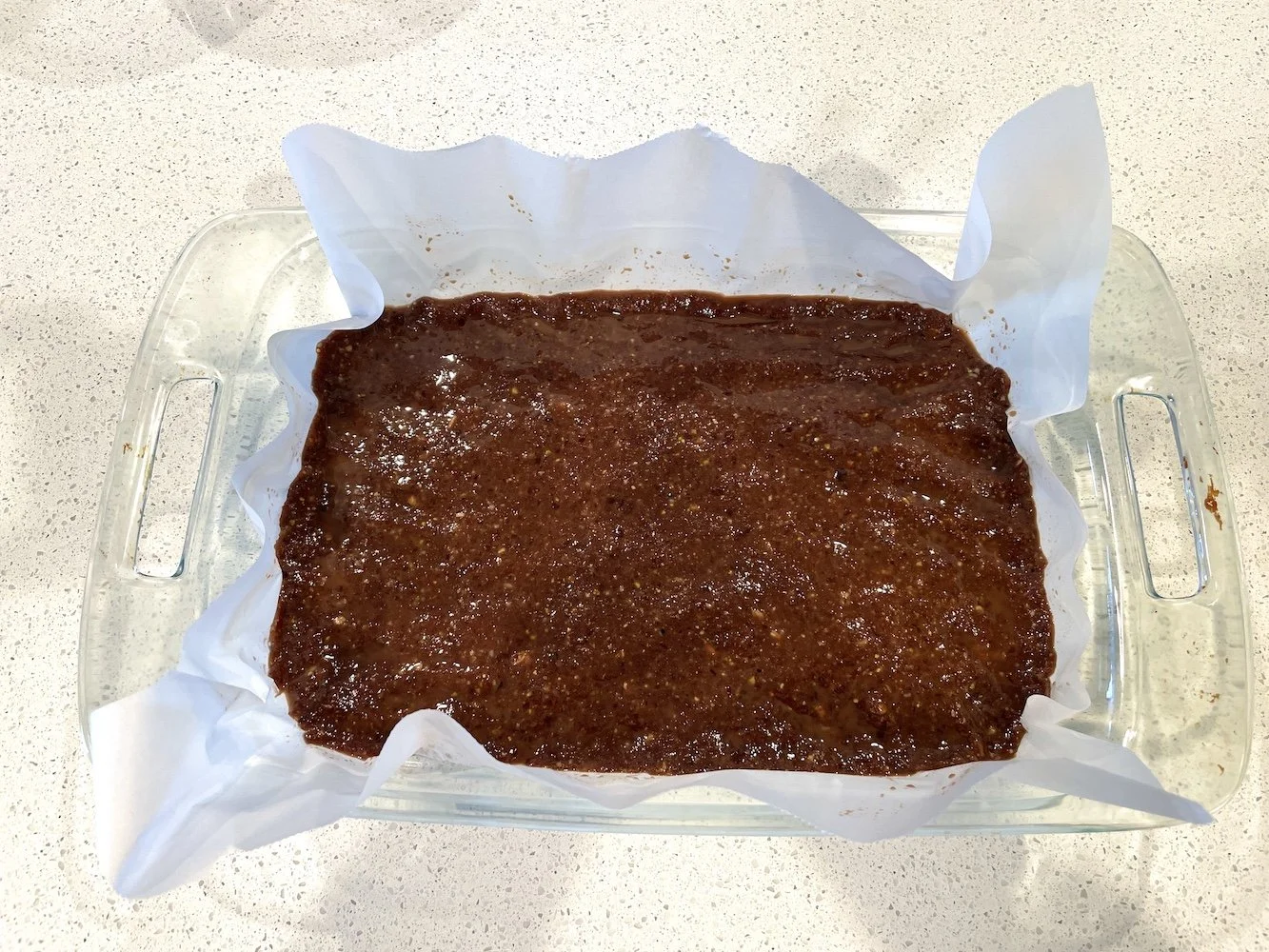 Date bar mixture pressed evenly into a parchment lined baking dish