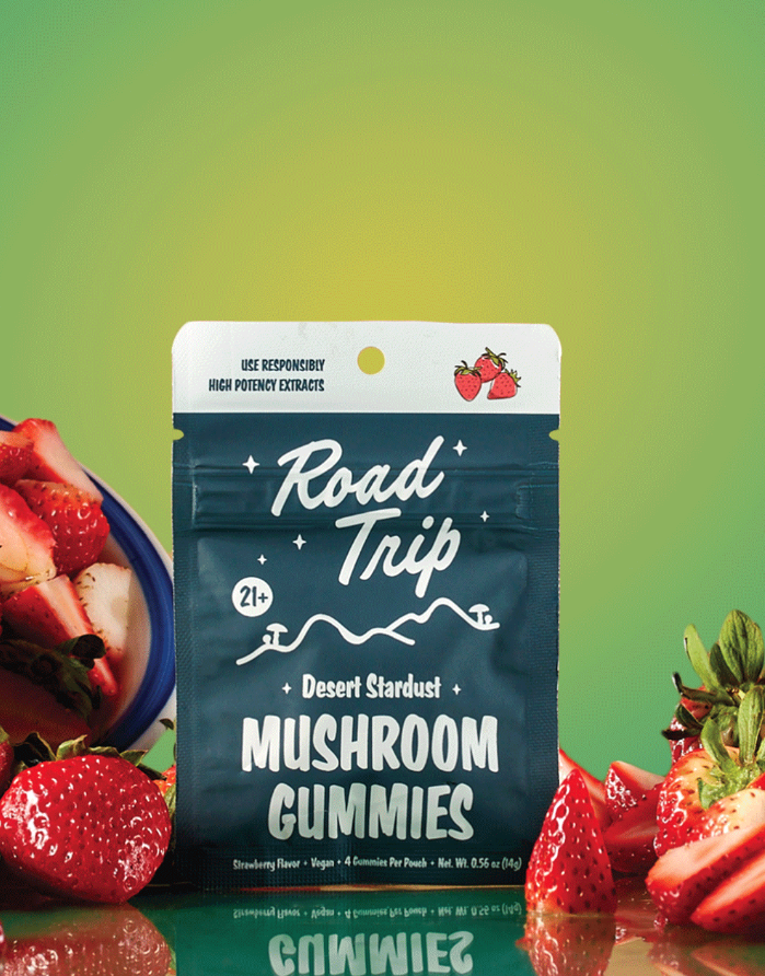 Road Trip Desert Stardust Strawberry mushroom gummies pouch surrounded by fresh sliced strawberries